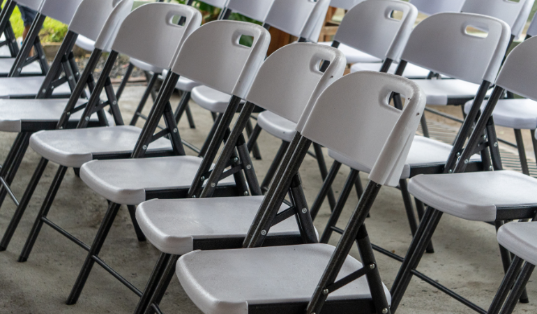 białe krzesła caterignowe ustawione obok siebie na betonowej posadzce 